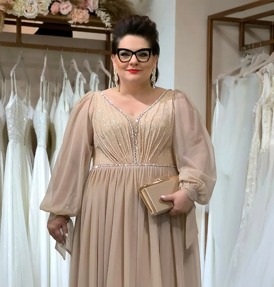 Kobieta w eleganckiej sukni wieczorowej plus size stojąca w salonie sukien ślubnych